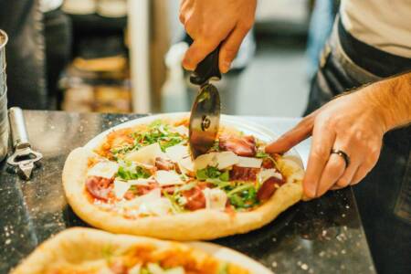Mann schneidet Pizza. Thema Essen, Pizza, Italienisches Essen