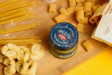 Auf einem rustikalen Holzbrett liegen großzügige Portionen Pasta, dazu Pesto.
